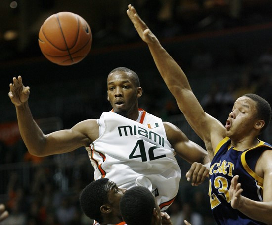 Miami's Raymond Hicks, left, looks for a loose ball after a block by North Carolina's Thomas Coleman during first-half ACC college basketball game at...