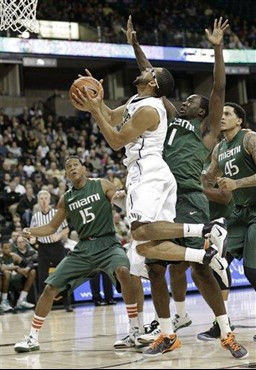Wake Forest's C.J. Harris, center, drives past Miami's Durand Scott, right, and Rion Brown, left, during the first half of an NCAA college basketball...