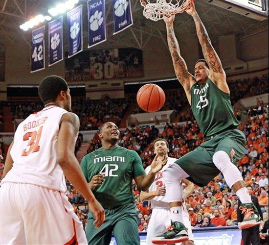 Clemson's Devin Booker (31) and Miami's Reggie Johnson (42) watch as Julian Gamble, right, hangs on the rim after dunking in the first half of their...