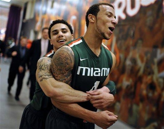 Miami's Shane Larkin, rear, embraces teammate Trey McKinney-Jones as they walk to the locker room after defeating Clemson 45-43 in an NCAA college...