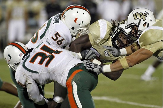 Central Florida running back Brynn Harvey, second from right, is stopped shy of a first down by Miami linebacker Sean Spence (31) and Marcus Robinson...