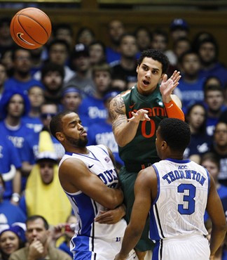 Duke's Josh Hairston and Tyler Thornton (3) defend against Miami's Shane Larkin (0) during the first half of an NCAA college basketball game in...