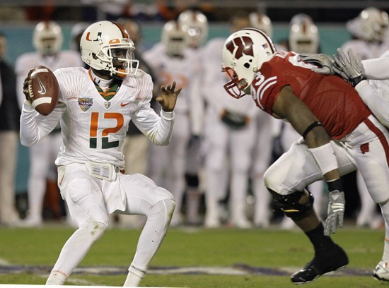 Miami quarterback Jacory Harris (12) looks for a receiver as he is pressured by Wisconsin defensive tackle Louis Nzegwu during the first half of the...