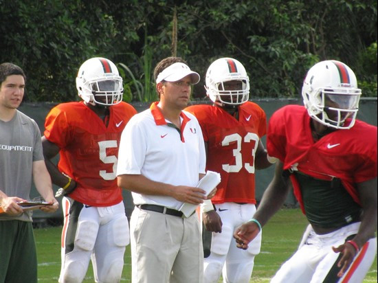 Offensive coordinator Jedd Fisch and running backs Mike James and Maurice Hagens look on as quarterback Jacory Harris participates in an offensive...