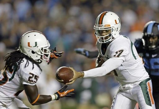Miami quarterback Stephen Morris (17) hands off to Dallas Crawford (25) during the first half of an NCAA college football game against North Carolina...