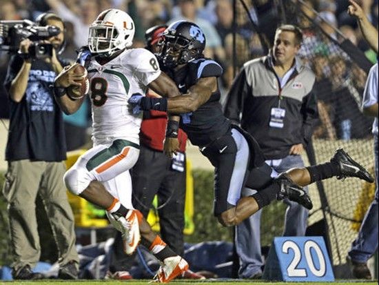 Miami's Duke Johnson (8) runs the ball as North Carolina's Brian Walker reaches for the tackle during the first half of an NCAA college football game...