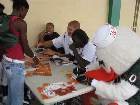 Jimmy Graham and Sebastian sign an autograph for a UM fan
