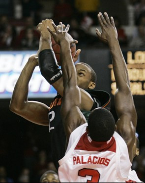 Miami's Raymond Hicks tries to see around the defense of Louisville's Juan Palacios as he takes a shot during the first half of their basketball game...