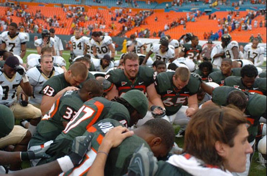 University of Miami Hurricane players and Wake Forest team members say a prayer at the end of the game. The Hurricanes beat the Deamon Deacons of...
