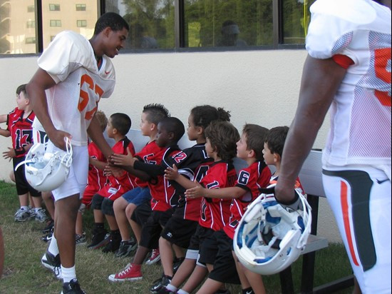 The Kendall Hammocks exchange high fives with Miami Football players after the training camp practice on Aug. 13.