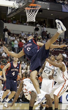 Saint Mary's forward Yusef Smith falls after making a shot against Miami. Defending for Miami are guard James Dews (23) and forward Raymond Hicks...