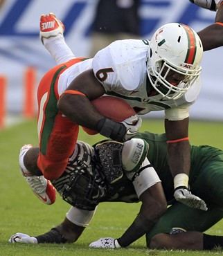 Lamar Miller gets tripped up by South Florida cornerback Kayvon Webster. (AP Photo/Chris O'Meara)