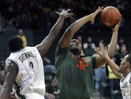 Miami's Reggie Johnson (42) shoots between Charlotte's K.J. Sherrill (2) and Pierria Henry (15) during the second half of Miami's 76-61 win in an NCAA...