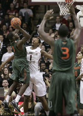 Miami's Durand Scott attempts a shot over the defense of Florida State's Xavier Gibson in the second half of an NCAA college basketball game on...
