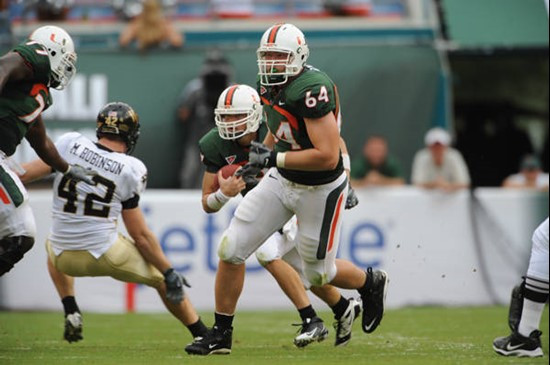 University of Miami Hurricanes offensive tackle Jason Fox #64 gets set to throw a block for quarterback Robert Marve #9 in a game against the Deamon...