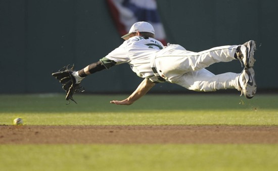 Miami shortstop Ryan Jackson leaps for a ball hit by Georgia's Joey Lewis for a base hit in the fifth inning of an NCAA College World Series baseball...