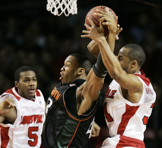 Miami's Raymond Hicks, center, and Louisville's Jerry Smith get tangled as they go for a rebound during the second half of their basketball game in...