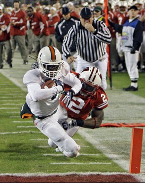 Miami running back Graig Cooper, left, runs for a 16-yard touchdown after getting by Wisconsin cornerback Jay Valai (2) during the first half of the...