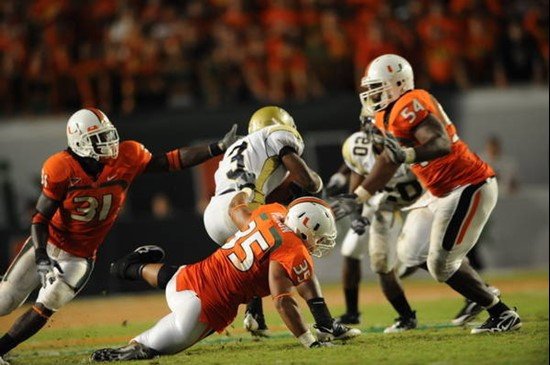 University of Miami defensive lineman Olivier Vernon #5 sacks the quarterback while teammates linebacker Sean Spence #31 and defensive lineman Micanor...