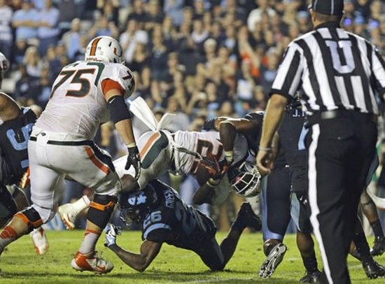 Miami's Dallas Crawford (25) dives into the end zone for the winning touchdown as North Carolina's Dominique Green (26) tries to make the stop during...