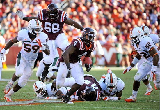 Virginia Tech's David Wilson (4) moves the ball against Miami's James Gains (59) and Denzel Perryman (52) during the first half of an NCAA college...