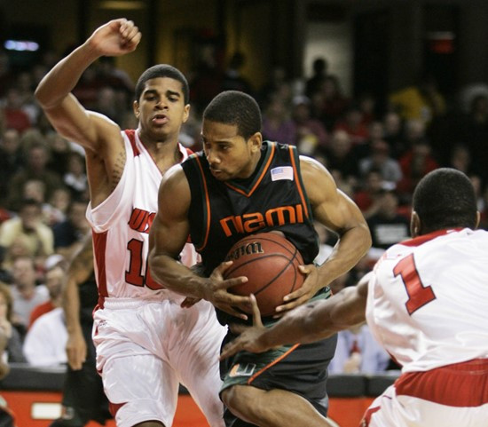 Miami's Anthony Harris tries to split the defense of Louisville players Edgar Sosa, left, and Terrence Williams as he drives to the basket during the...