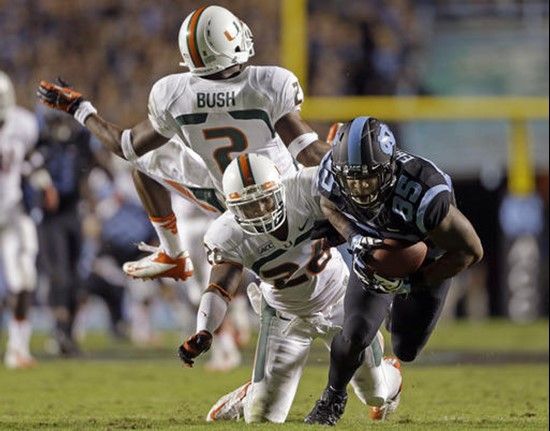 North Carolina's Eric Ebron (85) gains some yardage following a pass reception as Miami's Deon Bush (2) and  Rayshawn Jenkins defend during the first...