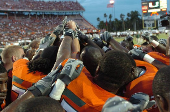 The University of Miami Hurricanes join hands for a moment of reflection before the game. Photo by Steven Murphy.