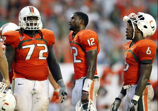 Miami players, from left, offensive lineman Brandon Washington, quarterback Jacory Harris and running back Lamar Miller react as they watch the...