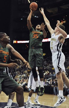 Miami center Kenny Kadji shoots against Georgia Tech center Daniel Miller, right, as Miami forward DeQuan Jones, left, looks on. (AP Photo/Gregory...