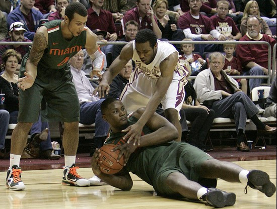 Miami's Reggie Johnson gathers up a loose ball as teammate Trey McKinney Jones, left, looks to help as Florida State's Michael Snaer comes to the...