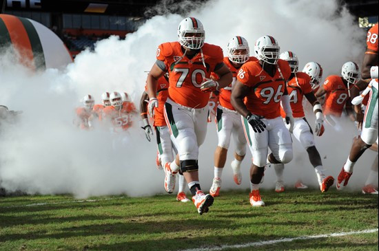 The University of Miami Hurricanes run through a tunnel of smoke before  a game against the Boston College Eagles at Sun Life Stadium on November 25,...