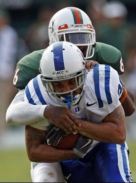 Duke wide receiver Donovan Varner, foreground, is tackled by Miami defensive back Randy Phillips in the fourth quarter of an NCAA college football...