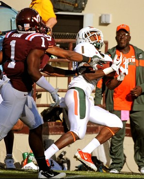 Miami's Allen Hurns (1) makes a catch against Virginia Tech's Antone Exum (1) and Cris Hill (9) during the first half of an NCAA college football game...