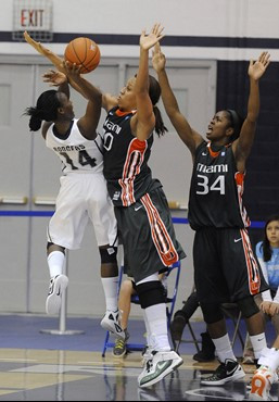 Georgetown guard Sugar Rodgers (14) goes up for a shot against the defense of Miami center Shawnice Wilson as Miami's Sylvia Bullock, right, helps on...
