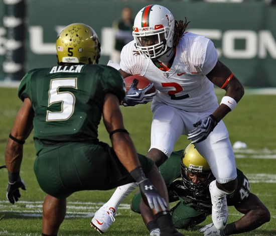 Miami running back Graig Cooper (2) gets away from South Florida safety Nate Allen (5) and linebacker Kion Wilson (42) on a first-quarter run during...