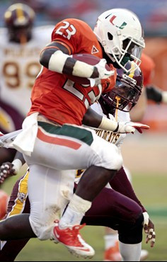 Miami's Eduardo Clements (23) jumps to avoid Bethune-Cookman's Al-Ghaffaar Lane, right, during the second half of an NCAA college football game in...