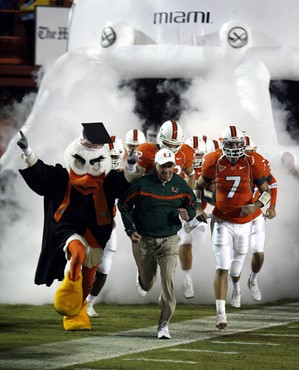 Miami Hurricanes head coach Larry Coker, center, runs onto the field with his team at the beginning of a college football game against Boston College,...