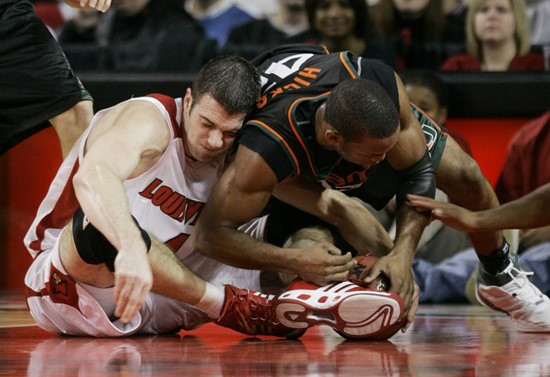 Louisville's David Padgett, left, and Raymond Hicks of Miami battle for a loose ball during the first half of their basketball game in Louisville,...