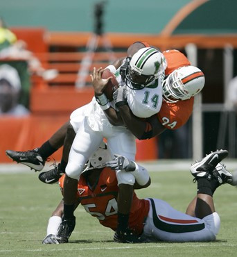 Marshall quarterback Bernard Morris (14) is sacked by Miami defensive tackle Teraz McCray, bottom, and defensive end Eric Moncur during the first...