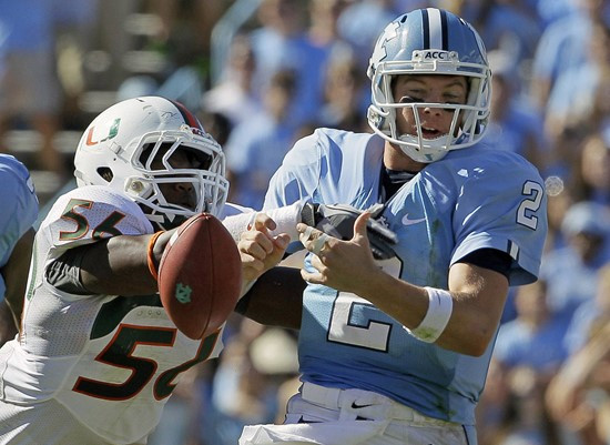 Miami's Marcus Robinson (56) hits North Carolina quarterback Bryn Renner (2) to force a fumble. (AP Photo/Gerry Broome)