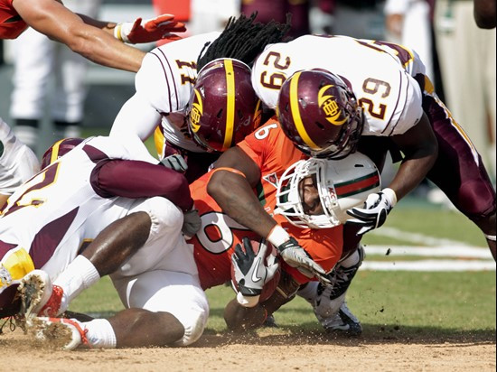 Miami's Lamar Miller (6) is brought down by Bethune-Cookman's Dion Hanks (29) and Reggie Sandilands (11) in the first half of an NCAA college football...