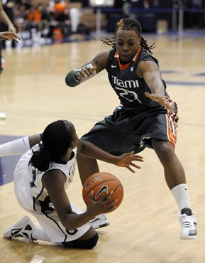 Miami guard Shanel Williams stands over Georgetown guard Sugar Rodgers, who fell to the court during first half of an NCAA college basketball game...