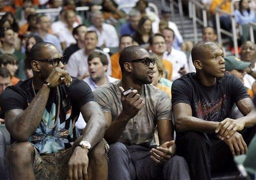 Miami Heat forward LeBron James, left, guard Dwyane Wade, center, and forward James Jones watch the first half of an NCCA college basketball game...